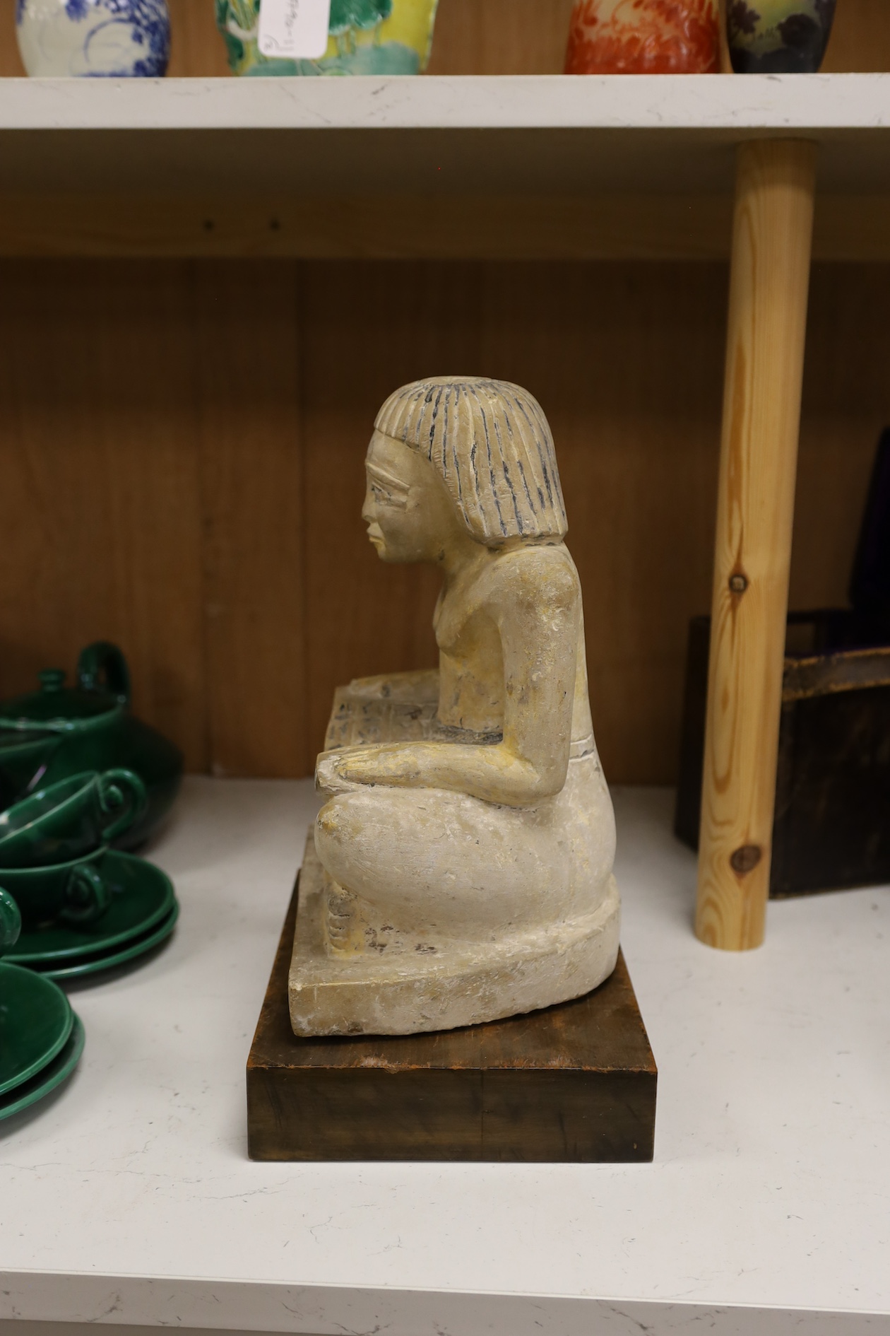 A carved stone Egyptian seated figure on wooden stand, 30cm high not including stand. Condition - fair to good